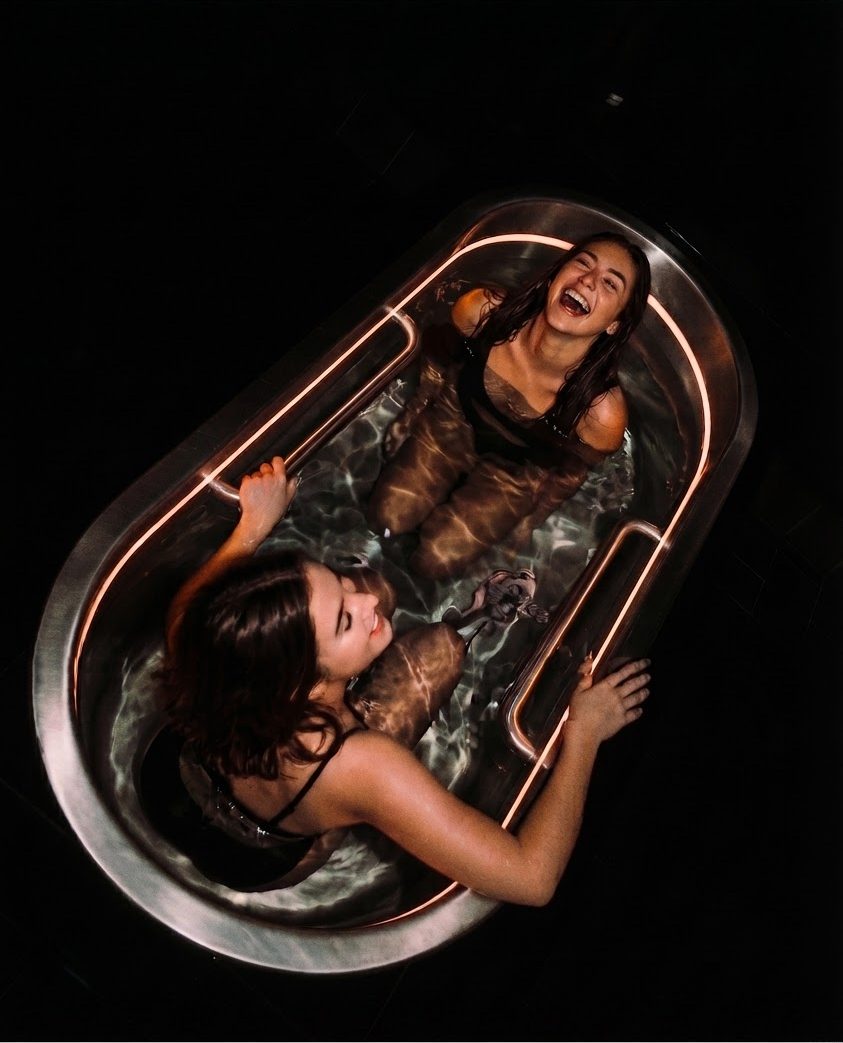 Two women in a dark cold plunge tub
